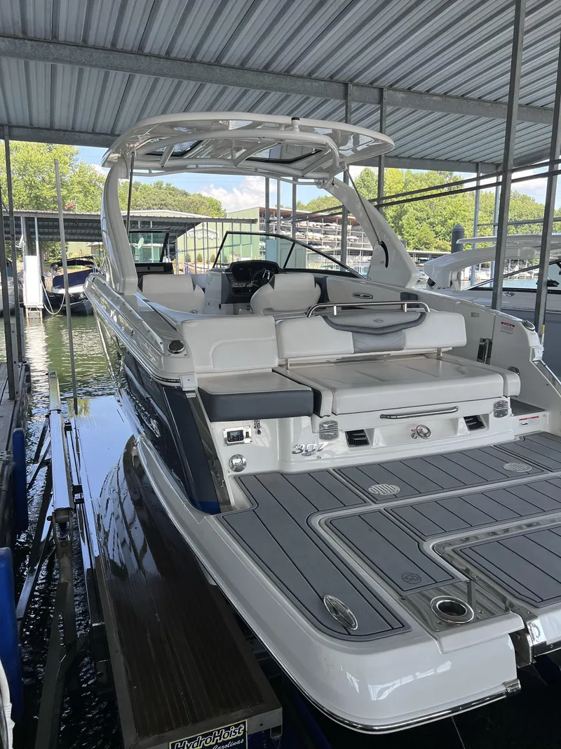 Slide: The Image of 2021 Chaparral 307 SSX boat docked under a covered marina. - 2