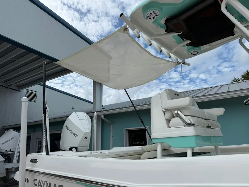 Slide: The Image of 2021 Caymas 26 HB boat with canopy, docked near a building under a cloudy sky. - 10