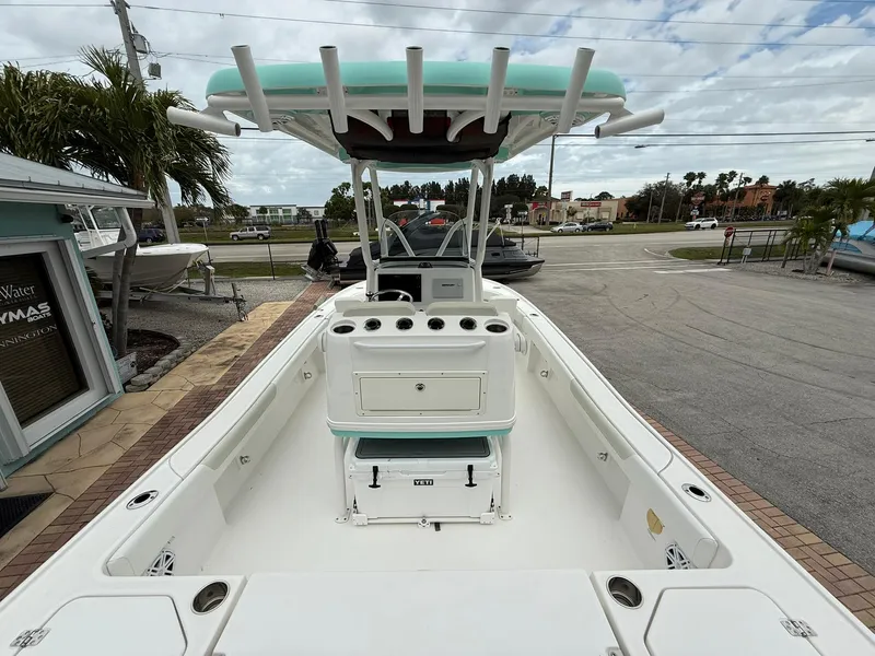 Slide: The Image of 2021 Caymas 26 HB boat, spacious deck, center console, teal canopy, parked outdoors. - 15