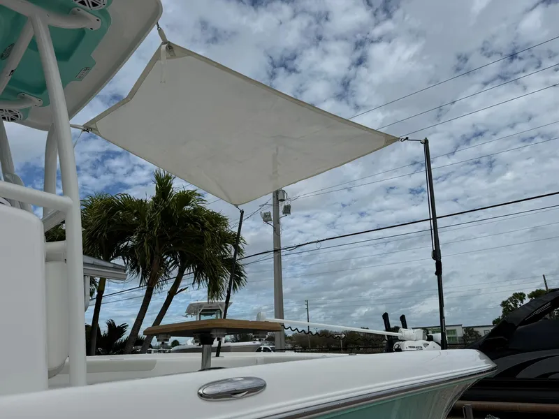 Slide: The Image of 2021 Caymas 26 HB boat with canopy under cloudy sky, palm trees in background. - 2