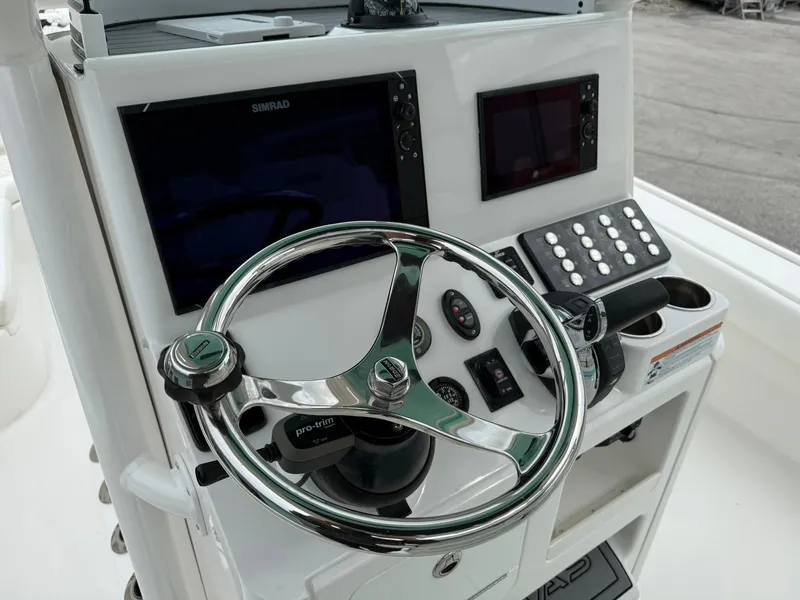 Slide: The Image of 2021 Caymas 26 HB boat dashboard with steering wheel, electronic displays, and control panel. - 21