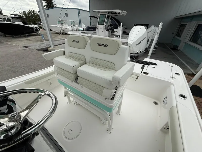 Slide: The Image of 2021 Caymas 26 HB boat with dual cushioned seats and steering wheel in a marina setting. - 24