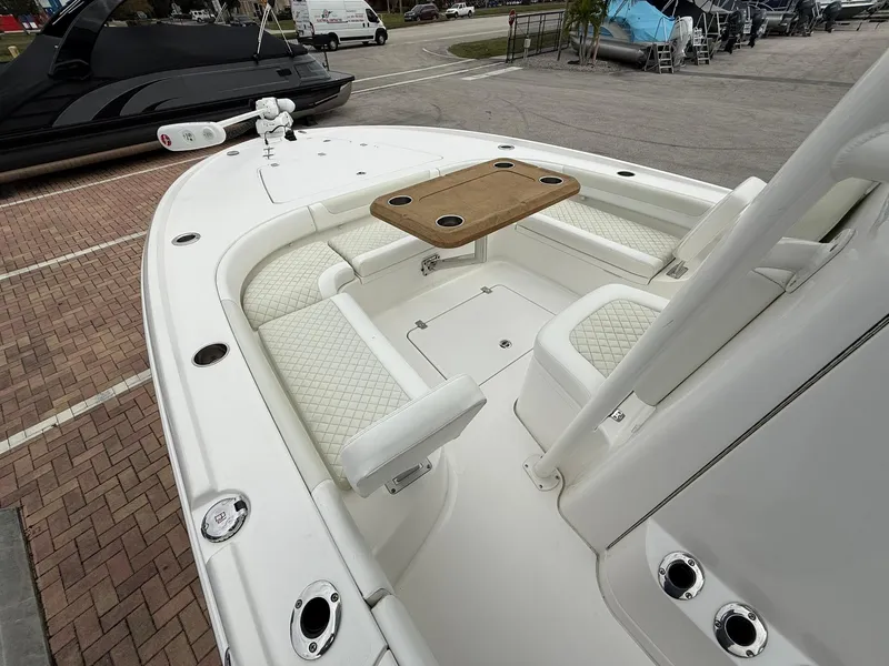 Slide: The Image of 2021 Caymas 26 HB boat interior with seating and table, docked outdoors. - 30