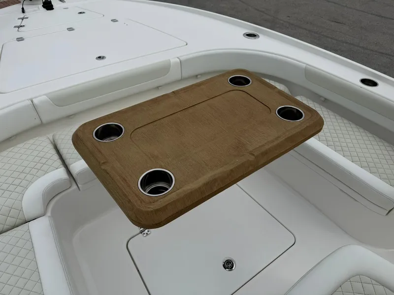 Slide: The Image of 2021 Caymas 26 HB boat with a wooden table and cup holders on deck. - 31
