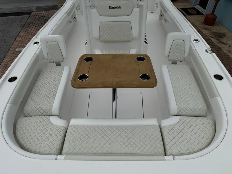 Slide: The Image of 2021 Caymas 26 HB boat interior with cushioned seating and a central wooden table. - 35