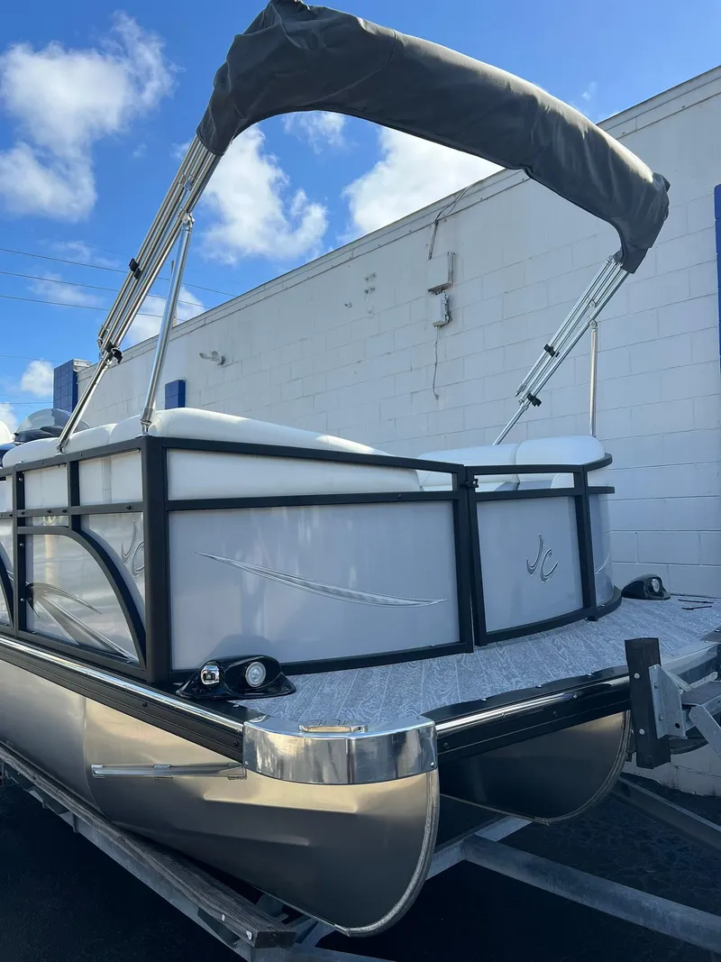 Slide: The Image of 2025 JC 201 Spirit TT Sport pontoon boat with canopy, docked outdoors. - 1