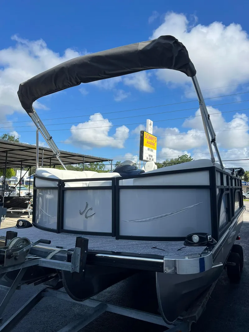 Slide: The Image of 2025 JC 201 Spirit TT Sport pontoon boat with canopy, parked outdoors under blue sky. - 2