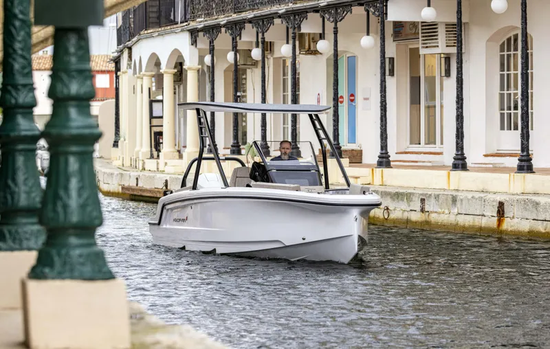 Slide: The Image of 2025 Axopar 22 T-Top Mediterrana cruising in a canal near historic buildings. - 3