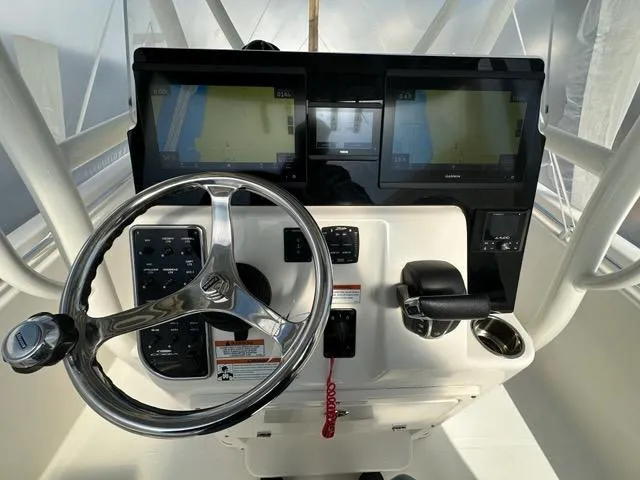 Slide: The Image of 2023 Cobia 220 Center Console boat dashboard with dual screens and steering wheel. - 2