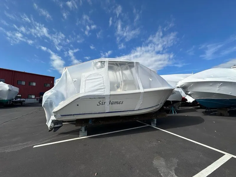Slide: The Image of 2023 Cobia 220 Center Console boat covered in protective wrap, parked outdoors. - 20