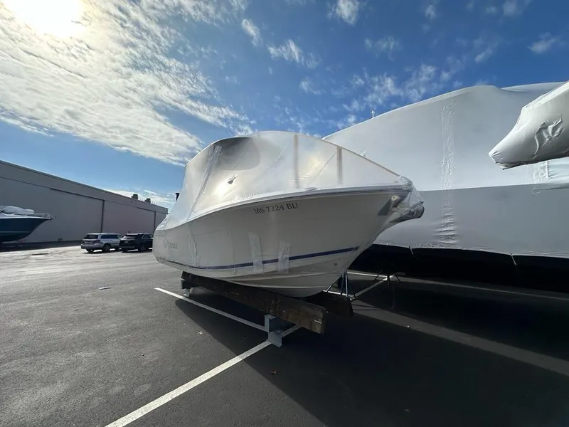 Slide: The Image of 2023 Cobia 220 Center Console boat covered in a parking lot under a cloudy sky. - 21