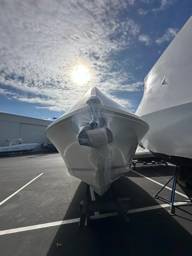 Slide: The Image of 2023 Cobia 220 Center Console boat wrapped in protective cover under a sunny sky. - 22