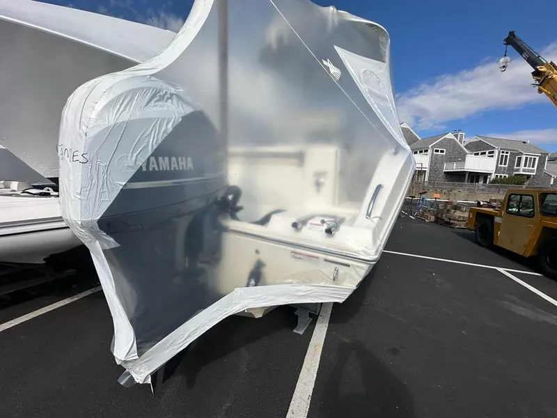 Slide: The Image of 2023 Cobia 220 Center Console boat wrapped in protective cover, parked outdoors. - 23