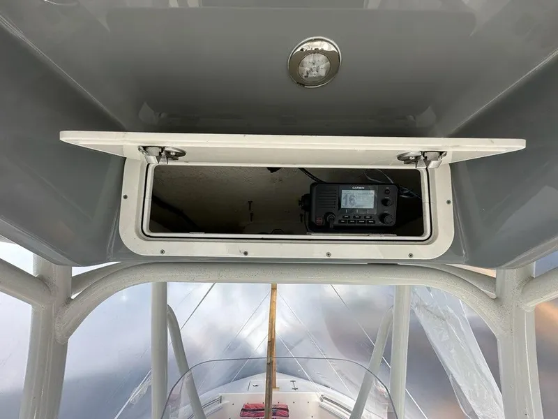 Slide: The Image of 2023 Cobia 220 Center Console boat with open storage compartment and electronic device. - 8