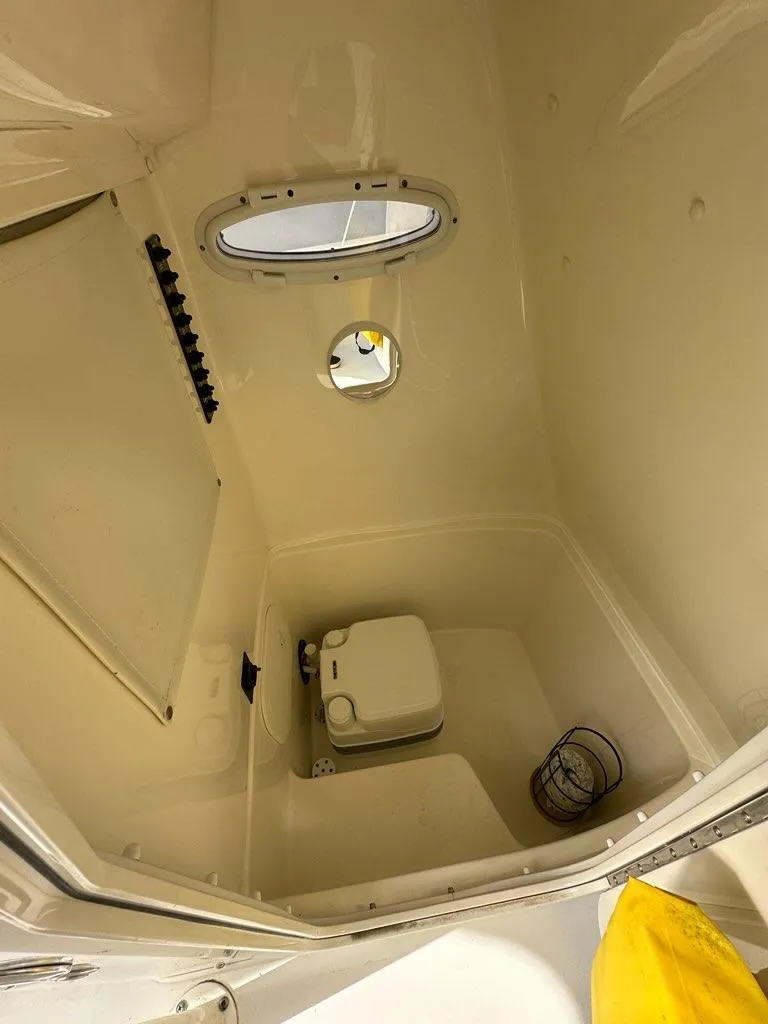Slide: The Image of 2023 Cobia 220 Center Console boat interior with compact toilet and porthole. - 9