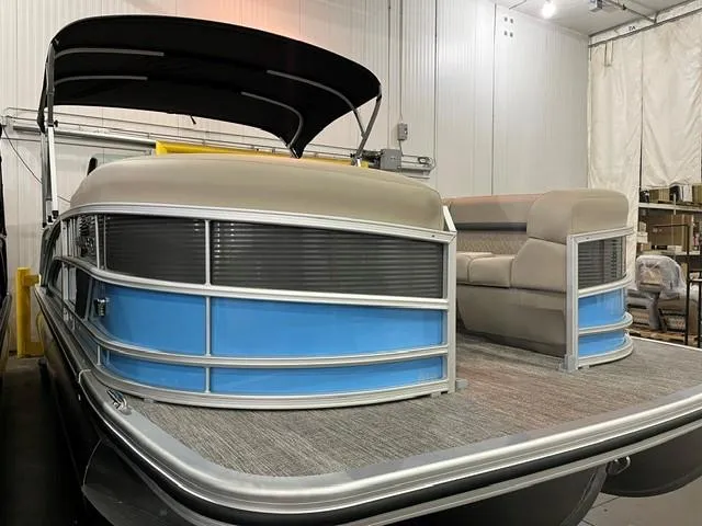 Slide: The Image of 2025 Bennington M22 Swingback pontoon boat in a showroom, featuring sleek design and comfortable seating. - 2