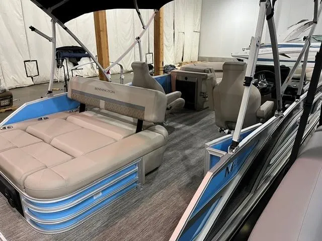 Slide: The Image of 2025 Bennington M22 Swingback pontoon boat interior with beige seating and blue accents. - 3