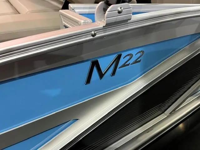 Slide: The Image of 2025 Bennington M22 Swingback boat, blue exterior detail with model name visible. - 6