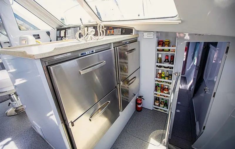 Slide: The Image of Modern yacht kitchen with stainless steel appliances, storage shelves, and a fire extinguisher. Chris White Atlantic 49. - 11