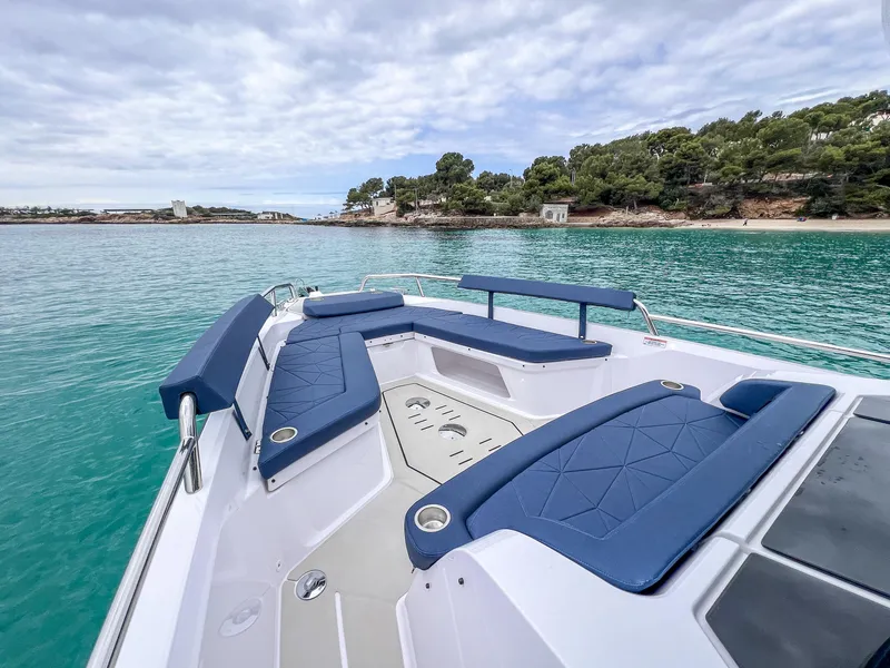 Slide: The Image of 2025 Axopar 29 XC Cross Cabin on turquoise water, featuring blue seating and scenic coastline. - 12