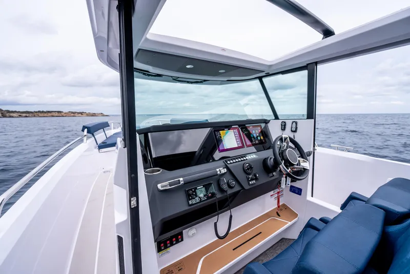 Slide: The Image of 2025 Axopar 29 XC Cross Cabin boat displayed in a showroom with other vessels. - 6