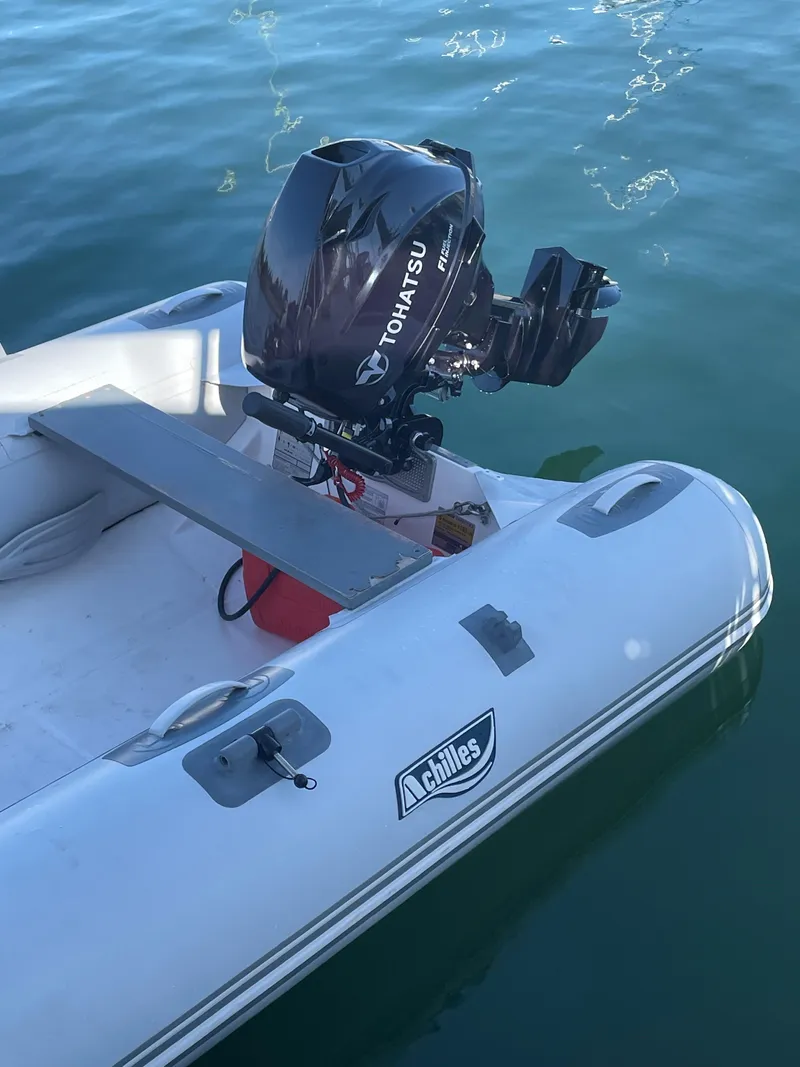 Slide: The Image of Inflatable Achilles boat with Tohatsu outboard motor on calm water. - 25