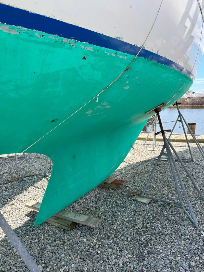 Slide: The Image of 1969 Ohlson 38 sailboat hull on stands, turquoise paint, outdoor setting. - 3
