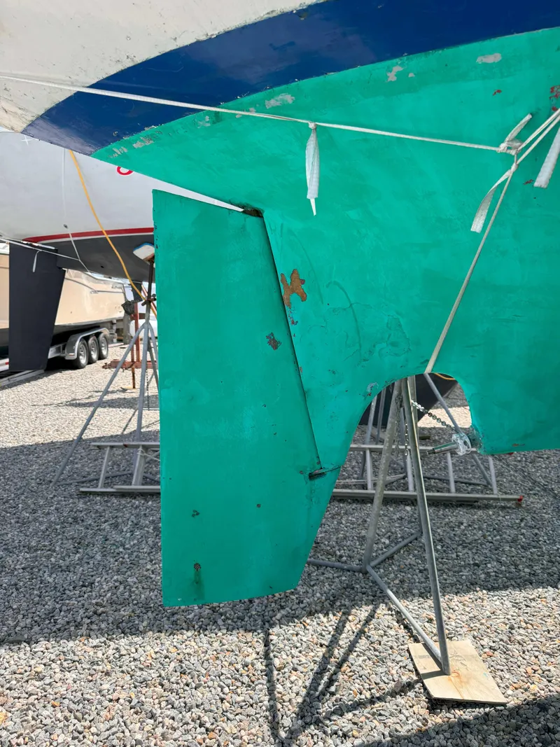 Slide: The Image of 1969 Ohlson 38 sailboat hull on stands, turquoise color, gravel ground. - 4