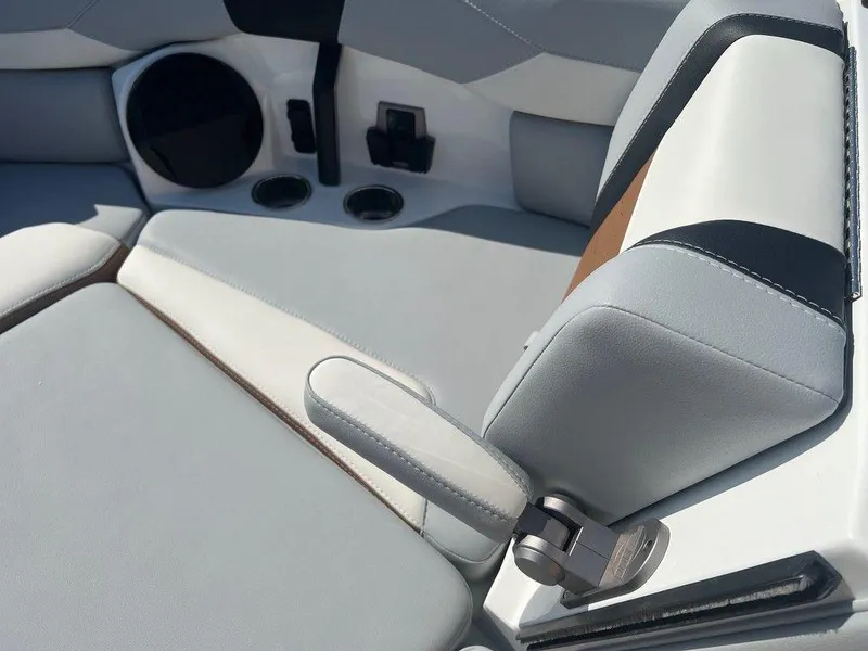 Slide: The Image of 2025 Malibu 23 LSV boat interior with gray and white seating, cup holders, and speaker. - 15