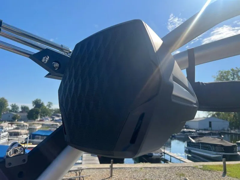 Slide: The Image of Close-up of a 2025 Malibu 23 LSV boat speaker with marina background. - 19