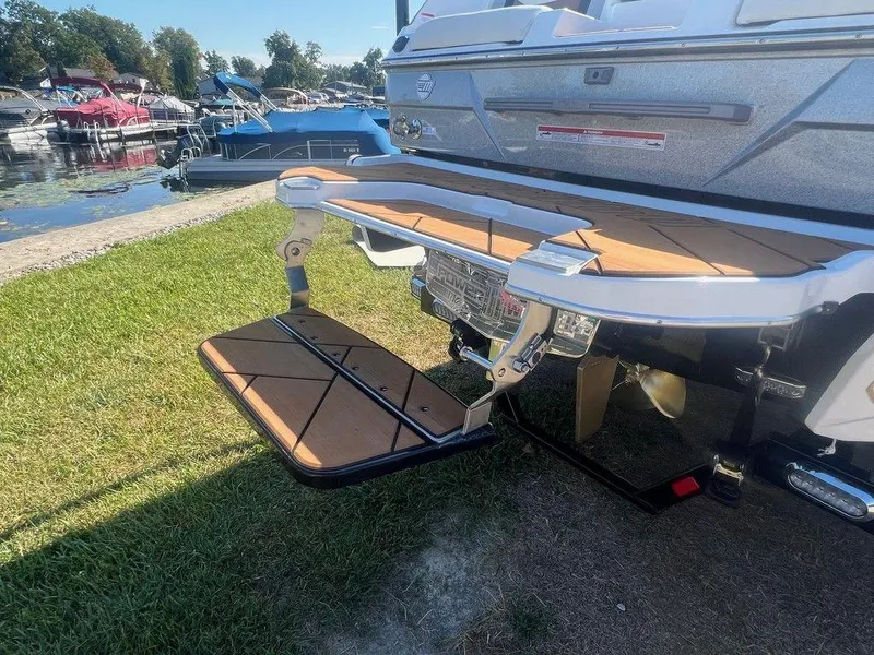 Slide: The Image of 2025 Malibu 23 LSV boat with extended swim platform at a lakeside marina. - 22