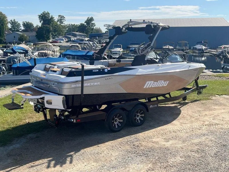 Slide: The Image of 2025 Malibu 23 LSV boat on trailer at marina, sunny day. - 3