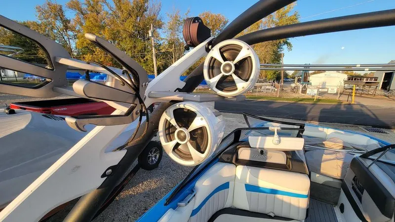 Slide: The Image of 2015 Malibu 24 MXZ boat with speakers and seating, docked outdoors. - 14