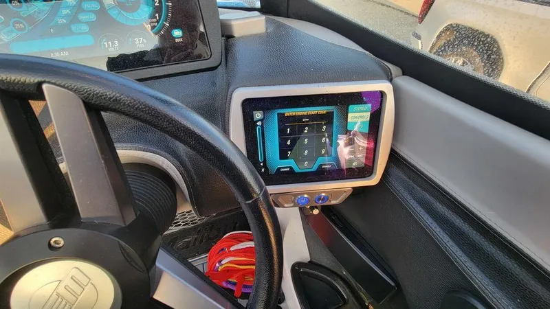 Slide: The Image of Dashboard of a 2015 Malibu 24 MXZ boat with touchscreen controls and steering wheel. - 16