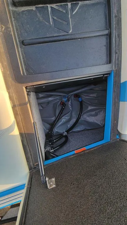 Slide: The Image of 2015 Malibu 24 MXZ boat storage compartment with cables and blue trim. - 18