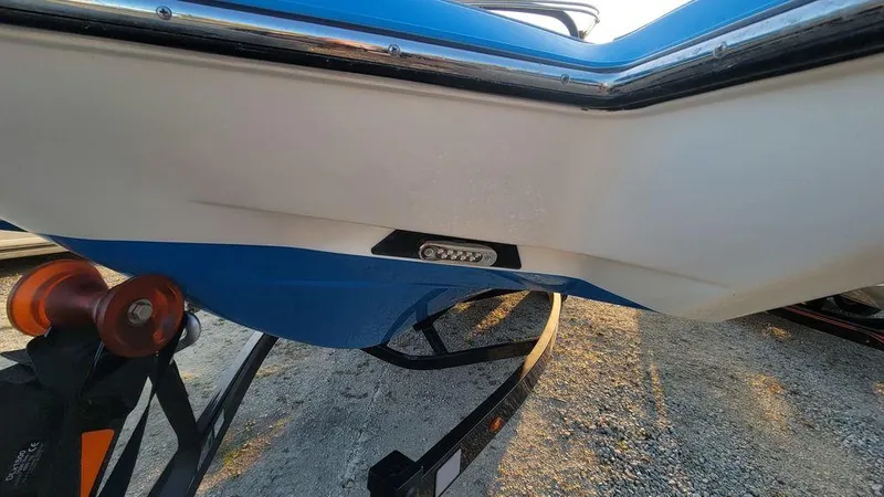 Slide: The Image of 2015 Malibu 24 MXZ boat hull with trailer, featuring blue and white design. - 25
