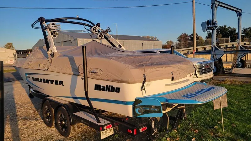 Slide: The Image of 2015 Malibu 24 MXZ boat on trailer, covered, parked outdoors. - 3