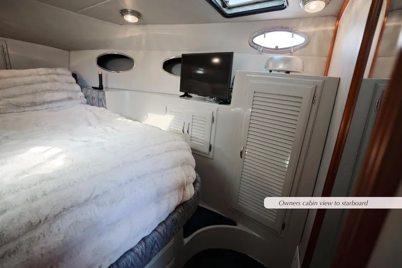 Slide: The Image of Owner's cabin in 1988 Mediterranean 38 Convertible yacht, featuring bed, TV, and storage. - 20