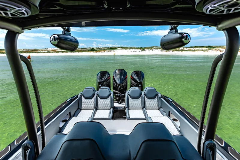 Slide: The Image of 2025 Glasstream GSX boat interior with multiple seats, overlooking clear green water and sandy shore. - 17