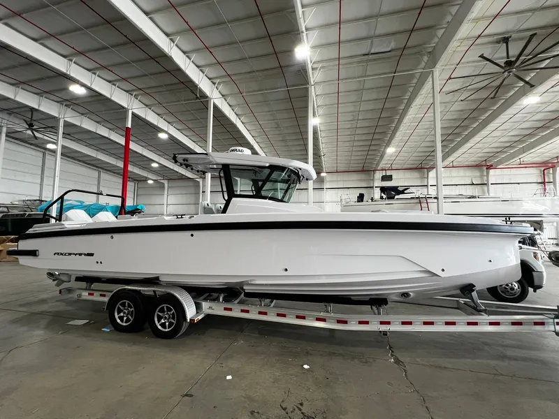 The Image of 2025 Axopar 29 CCX boat on trailer, sleek white design, parked outdoors. - 0