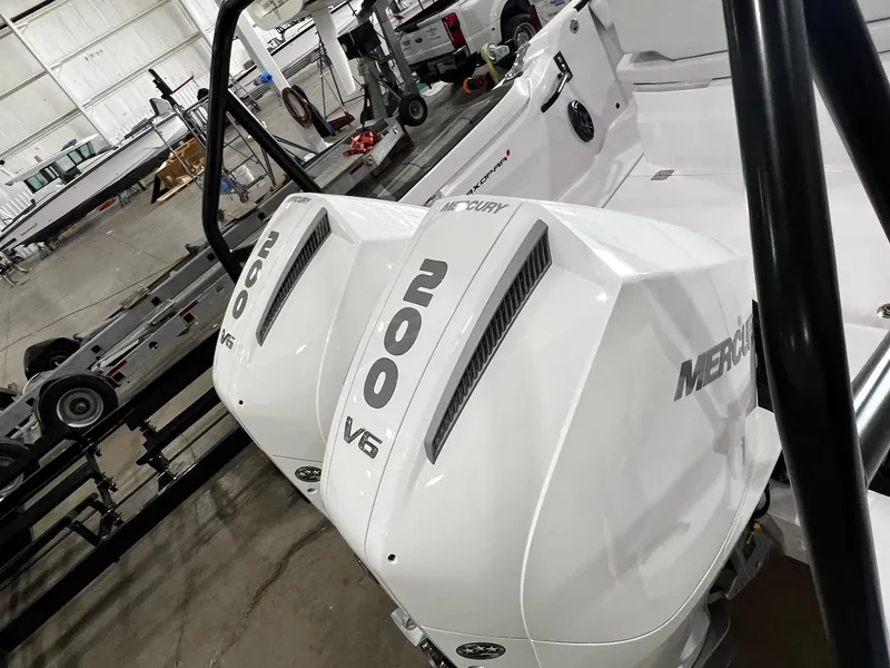 Slide: The Image of 2025 Axopar 29 CCX boat, sleek white exterior, docked near grassy sidewalk. - 7