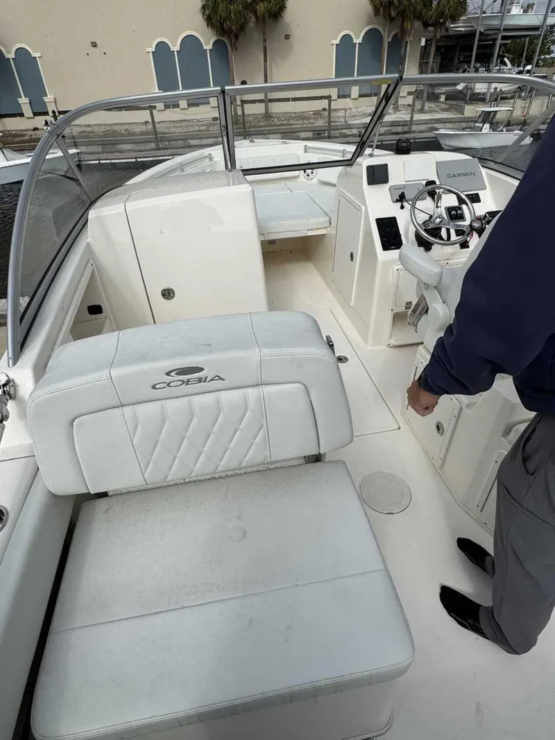 Slide: The Image of 2023 Cobia 220 DC boat interior with white seating and steering console. - 4