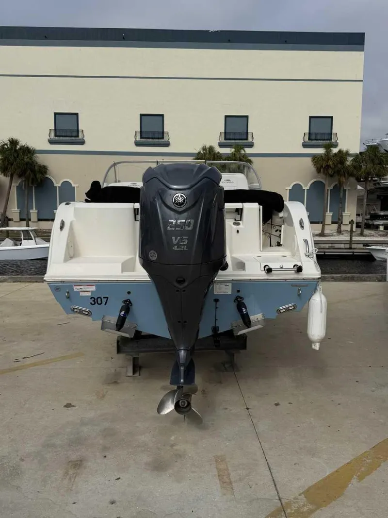Slide: The Image of 2023 Cobia 220 DC boat with Yamaha V6 engine, parked outdoors. - 6