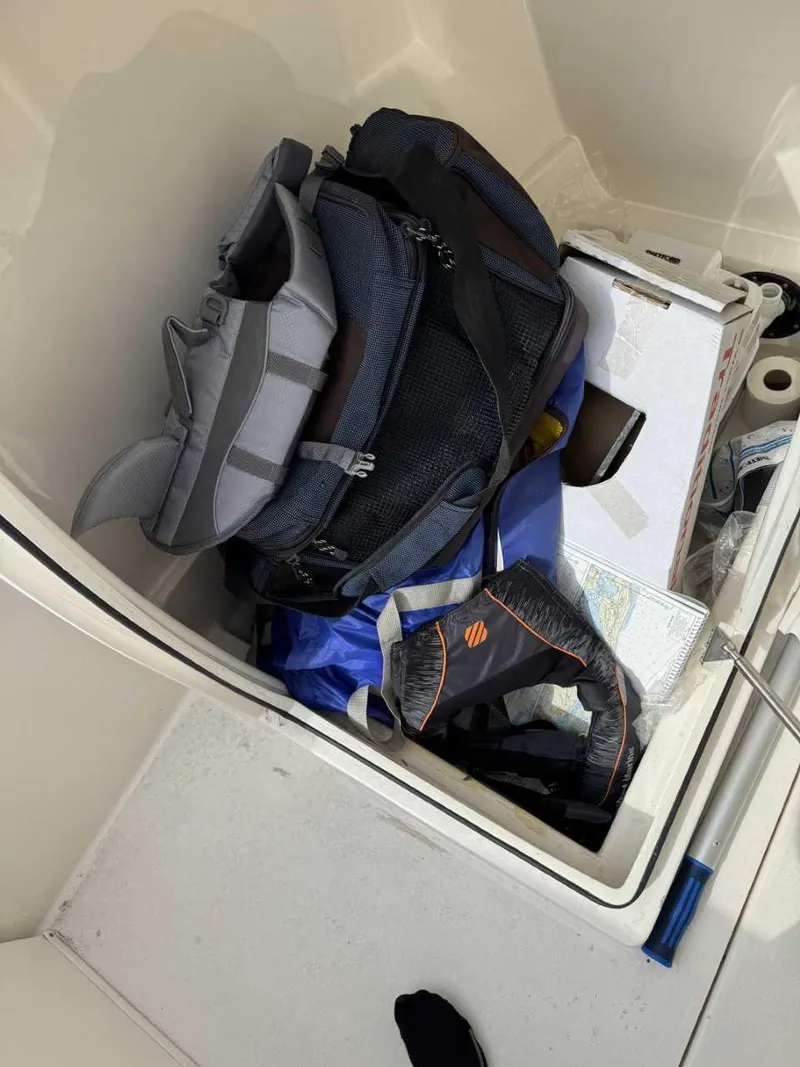 Slide: The Image of Storage compartment on a 2023 Cobia 220 DC boat with bags and gear. - 9