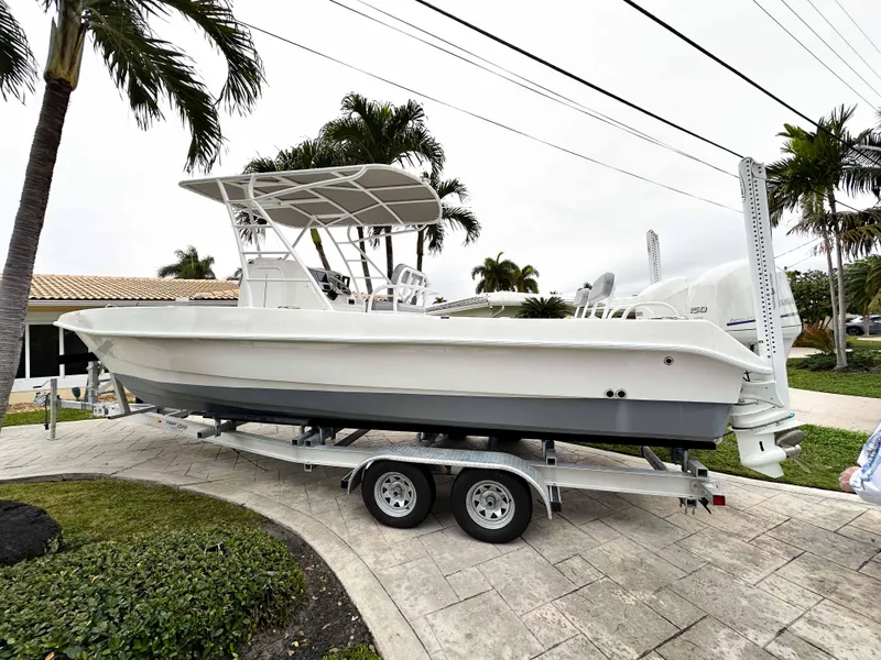 Slide: The Image of 2013 Twin Vee 26 Center Console boat on trailer, parked near palm trees. - 1