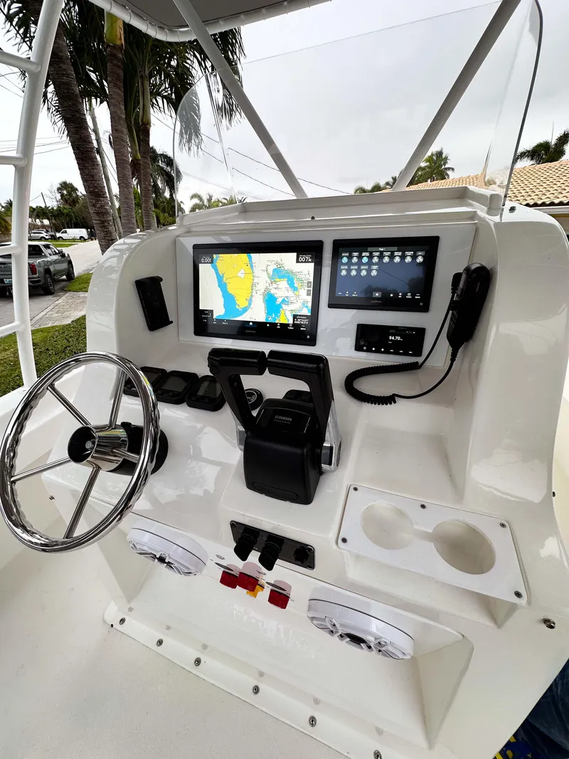 Slide: The Image of 2013 Twin Vee 26 Center Console boat dashboard with navigation screens and steering wheel. - 14