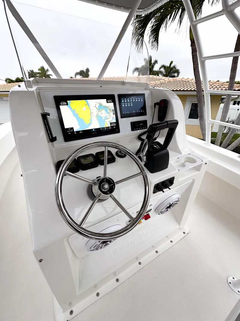 Slide: The Image of 2013 Twin Vee 26 Center Console boat helm with navigation screens and steering wheel. - 15