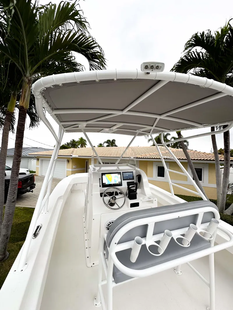 Slide: The Image of 2013 Twin Vee 26 Center Console boat with canopy, parked near palm trees. - 21