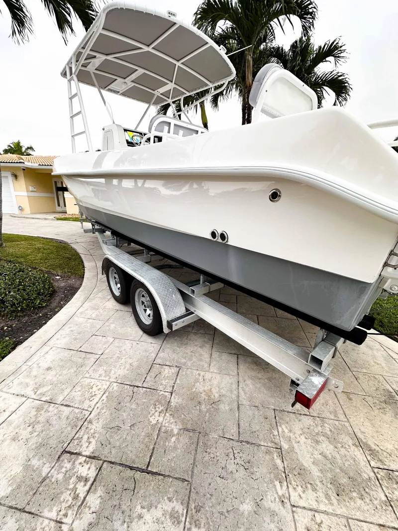 Slide: The Image of 2013 Twin Vee 26 Center Console boat on trailer, parked in driveway with palm trees. - 29
