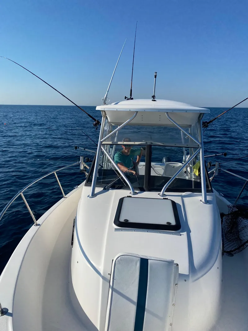 Slide: The Image of 1996 Trophy 2352 Walkaround boat on open sea, clear sky, fishing rods visible. - 3